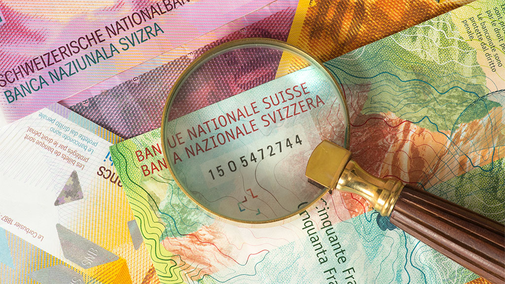 Lupe und Schweizer Banknoten